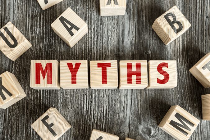 Wooden letter blocks spelling the word “MYTHS” on a rustic wooden background.