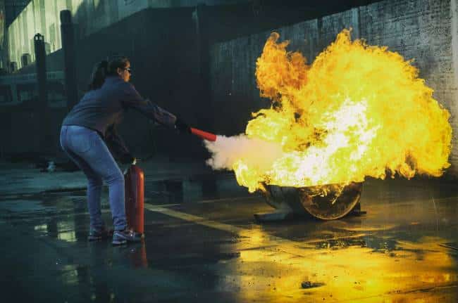 A woman uses a fire extinguisher to put out a fire